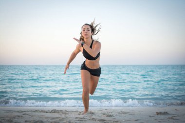 Kumsalda koşan zayıf, güzel bir kız.