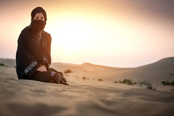 砂漠の上の日没空に対する黒い伝統的な服の若い女性ベドウィン — ストック写真