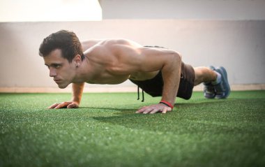 Açık havada şınav çeken kendinden emin bir sporcu.