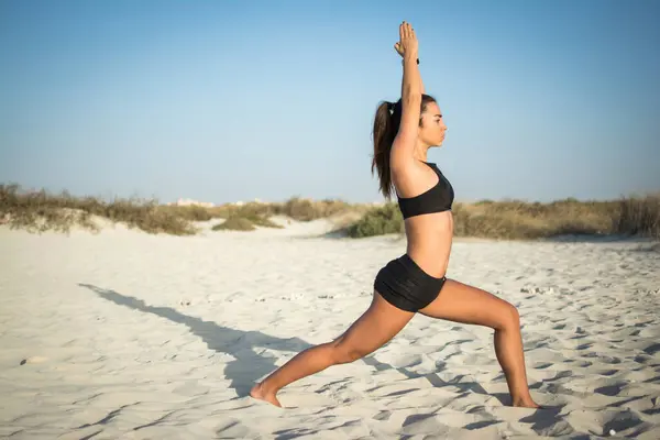 身材苗条的年轻女子在海滩上低矮地摆着瑜伽姿势 — 图库照片
