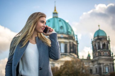 Berlin caddesinde yürürken cep telefonuyla konuşan güzel bir iş kadını.