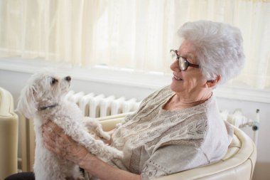 Evde köpeğini tutan mutlu yaşlı kadın.