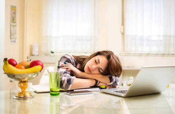 ノートパソコンと本の近くでデスクで寝ている若い女性の学生 — ストック写真