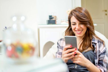 gülümseyen genç kadın evde cep telefonunuzun