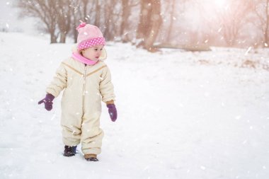 Dışarıda karda yürüyen tatlı küçük kız.