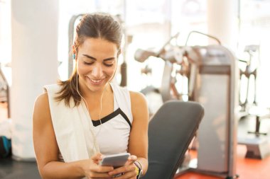 Sportif kız spor salonunda akıllı telefon kullanıyor.