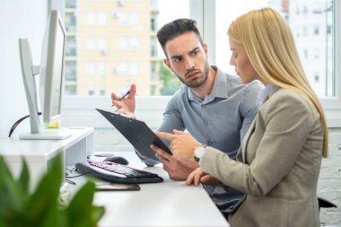 İş adamı ve iş kadını pano ile ofiste iş projesini tartışıyorlar.