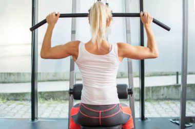 Genç sarışın kadın spor salonunda egzersiz yapıyor.