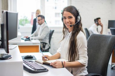 Ofiste çalışan güzel ve neşeli genç bir kadın telefon operatörü portresi.