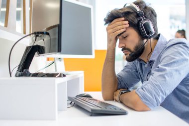 Çağrı merkezi kulaklığı takan yakışıklı genç adam baş ağrısı çekiyor.