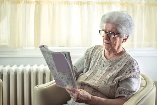 在家里解决填字游戏的老年妇女 — 图库照片