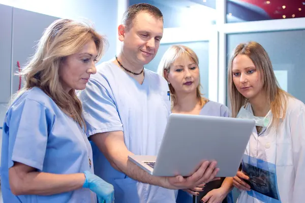 Hastanede dizüstü bilgisayardaki sağlık raporlarını inceleyen bir grup sağlık çalışanı