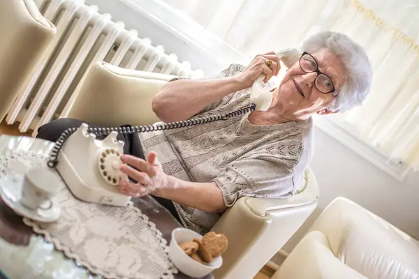 Χαμογελαστή Γιαγιά Μιλώντας Στο Σταθερό Τηλέφωνο Περιστροφικό Ενώ Κάθεται Στην — Φωτογραφία Αρχείου
