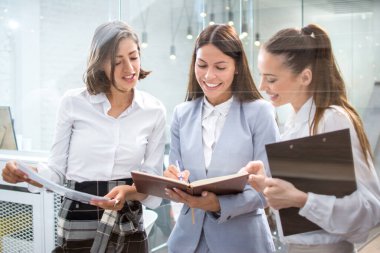 Belgeleri olan iş kadınları ofiste birlikte çalışıyorlar.