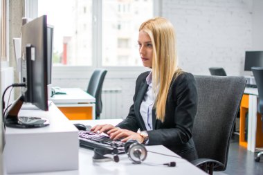 Ofiste bilgisayarla çalışan güzel sarışın kadın.