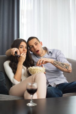 Harika bir çift televizyon seyrediyor ve evde kanepede otururken patlamış mısır yiyor.