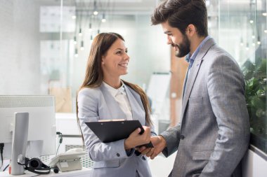 İki genç iş adamı ofiste belgeler hakkında konuşuyor.