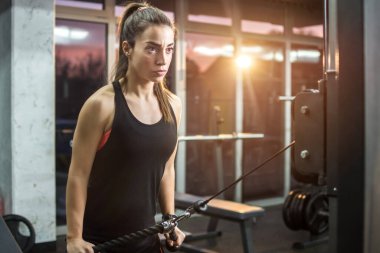 Sportif kız spor salonunda egzersiz makinesiyle egzersiz yapıyor.