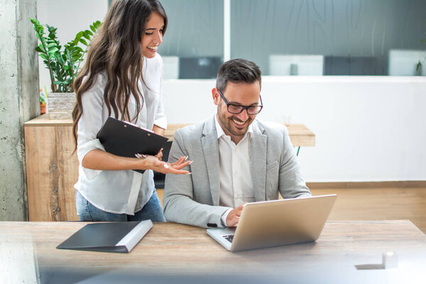 Деловые мужчины и женщины обсуждают финансовые данные на ноутбуке в офисе