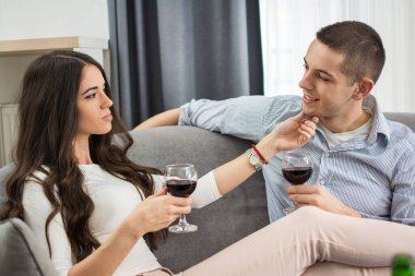 Şarap içen ve erkek arkadaşını baştan çıkaran genç bir kadın.