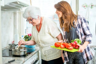 Büyükannesi ve torunu mutfakta birlikte yemek pişiriyorlar.