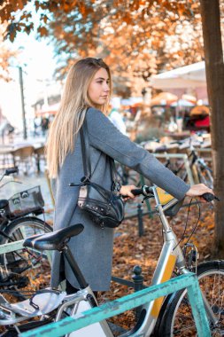 Şehir trafiğinden kaçmaya çalışan bisikletli genç bir kadın. Kiralık bisiklete binen bir kız