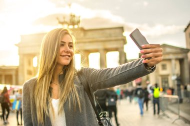 Berlin, Almanya 'da Brandenburg Kapısı önünde selfie çeken güzel sarışın kız.
