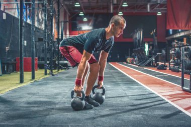 Spor giyim sektöründe formda bir adam spor salonunda ağırlık kaldırıyor.
