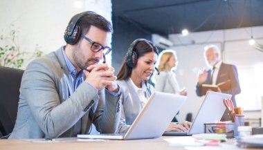 Kulaklık takıp dizüstü bilgisayarlara bakan düşünceli ya da endişeli müşteri destek ajanı