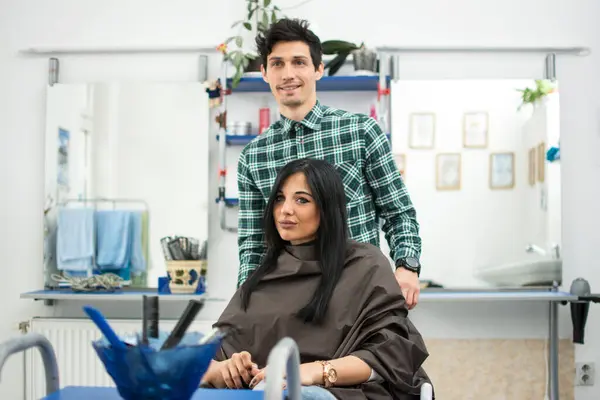 Male hairdresser makes hairstyle for a girl at hair salon