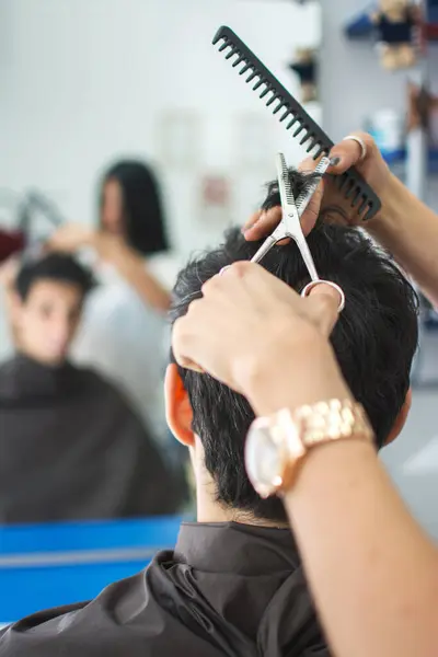 Close up image of hairdresser trimming black hair with scissors