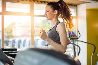 Spor salonunda koşu makinesinde çekici bir sporcu.