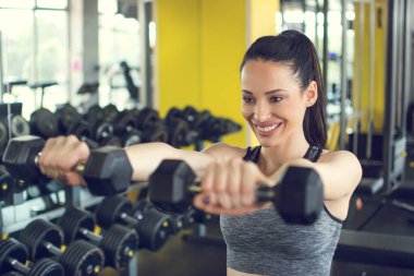 Spor salonundaki ağırlık çalışan kadın portresi.