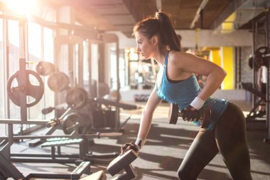 Sportif kız spor salonunda ağırlık kaldırma