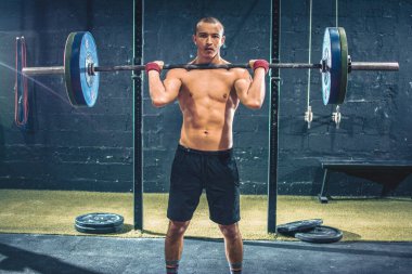 Spor salonunda ağırlık egzersizi yapan zinde bir genç.