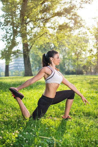 Young woman doing stretching exercise outdoors in the morning