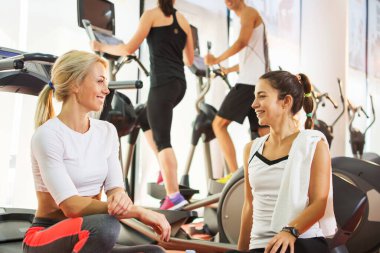 Spor salonundaki egzersizden ve iletişim kurmaktan dinlenen neşeli genç kızlar..