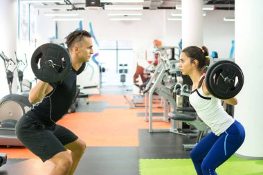 Spor salonunda kadın müşteriyle ağırlık kaldırma antrenmanında erkek kişisel antrenörü..