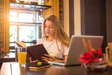 Kitap ve dizüstü bilgisayarlı lise öğrencisi sınava hazırlanıyor.