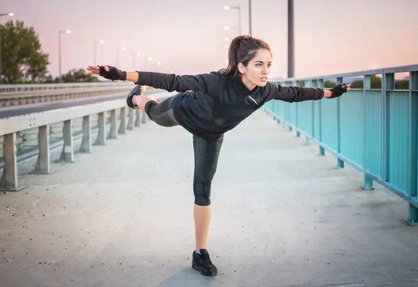 健康的年轻女运动员单腿站立 双手高举 进行平衡运动 — 图库照片