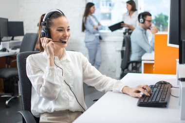 Kadın müşteri hizmetleri çalışanı, çağrı merkezi gülen operatörü, telefon kulaklığı ofiste çalışıyor..