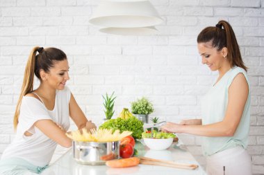 İkiz kardeşler evdeki mutfakta yemek hazırlıyorlar.