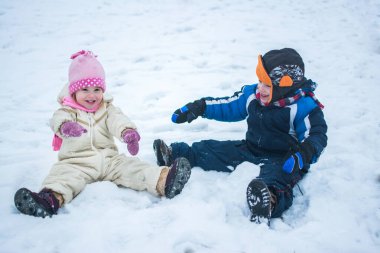 Mutlu çocuklar kış tatilinde karda oynuyorlar.