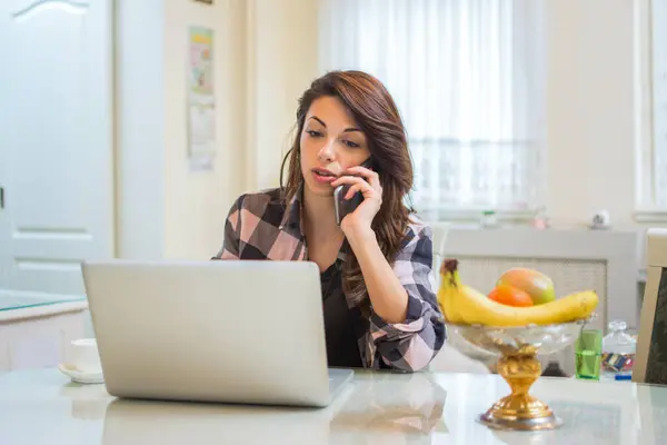 Młoda Kobieta Rozmawiająca Przez Telefon Komórkowy Korzystająca Laptopa Domu — Zdjęcie stockowe