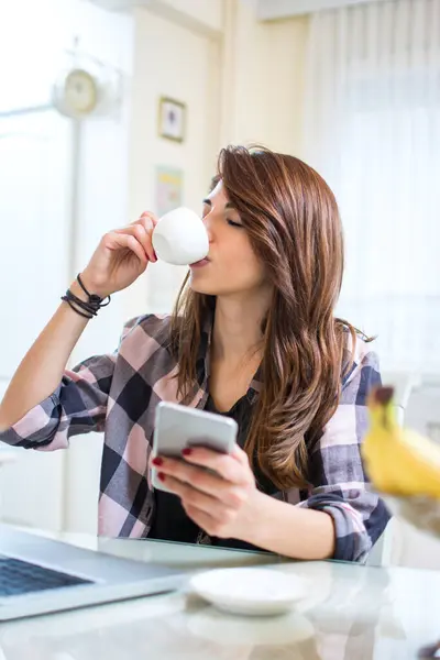 コーヒーや紅茶を飲んでスマートフォンを使用する若い女性 — ストック写真