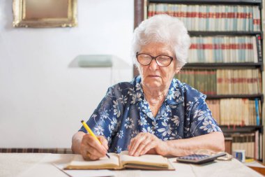 Kıdemli kadın evde bütçe hesaplıyor.