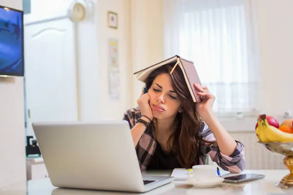 ノートパソコンで宿題をし 頭にノートを握る退屈な女性の学生 — ストック写真