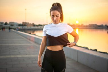 Günbatımında spor giysili, kaldırımda dikilen genç, ciddi bir jimnastik kadın..