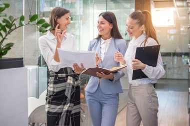 Güzel iş kadınları ofis lobisinde evrak işlerini tartışıyor..