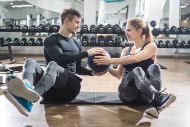 Sportif fitness çifti spor salonunda ilaç topuyla karın egzersizi yapıyor..